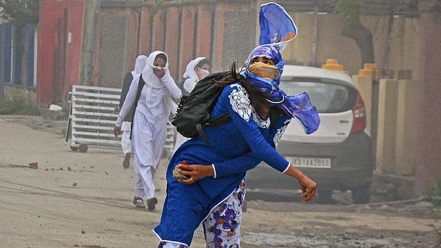 A girl student pelts a stone at security personnel during clashes in the vicinity of Lal Chowk in Srinagar. (Photo: PTI)