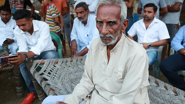Sumit’s father Biram Singh is at the centre of a crowd of Thakurs gathered outside his house, discussing the violence that killed his son. (Photo: Abhay Sharma/<b>The Quint</b>)