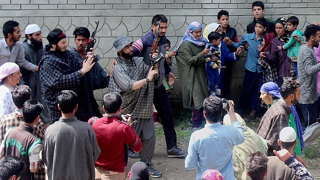 Suspected militants brandish their guns and shout slogans at the funeral of a slain colleague, at Qoimoh in Kulgam district of south Kashmir, 7 May 2017. (Photo: PTI)