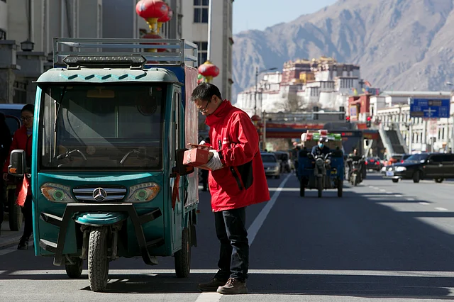 A delivery man of Alibaba’s logistics unit Cainiao checks his phone as he delivers a parcel in Lhasa on 14 January 2018.
