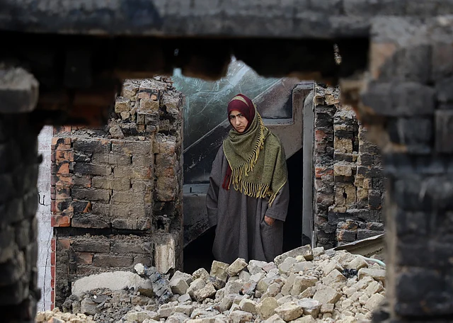 Ghulam’s neighbour looks over from the remains of his house. 
