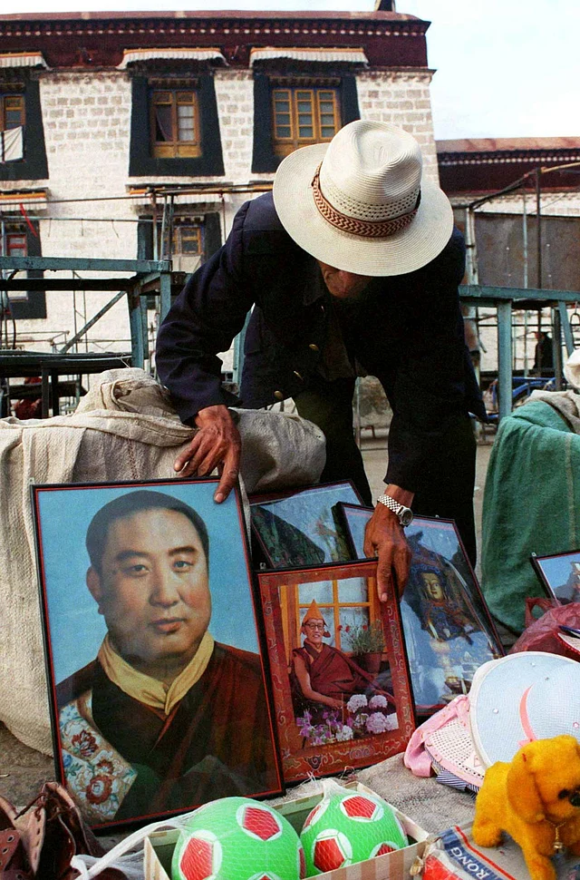 A Tibetan vendor moves a photograph of the Panchen Lama to reveal a picture of a young Dalai Lama in front of the Jokhang Temple in Lhasa on 26 May 1998.
