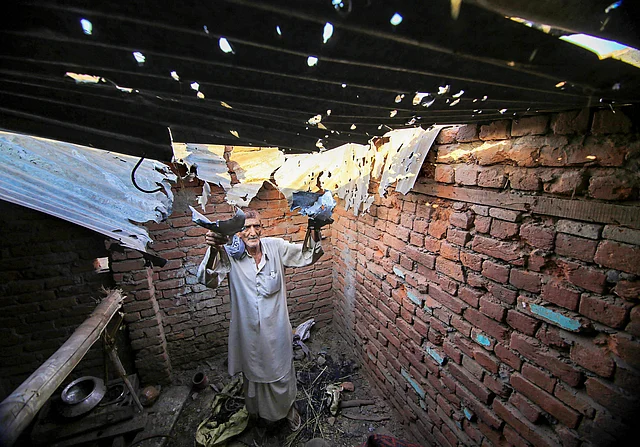 A villager shows a roof, claimed to be damaged after firing from the Pakistani side.