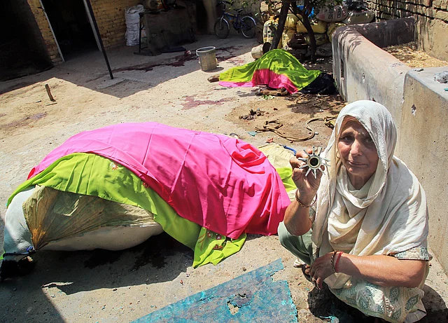 A woman shows parts of mortar shell found near the carcasses of an animal, allegedly fired from the other side at Changia village near Arnia sector in Jammu.