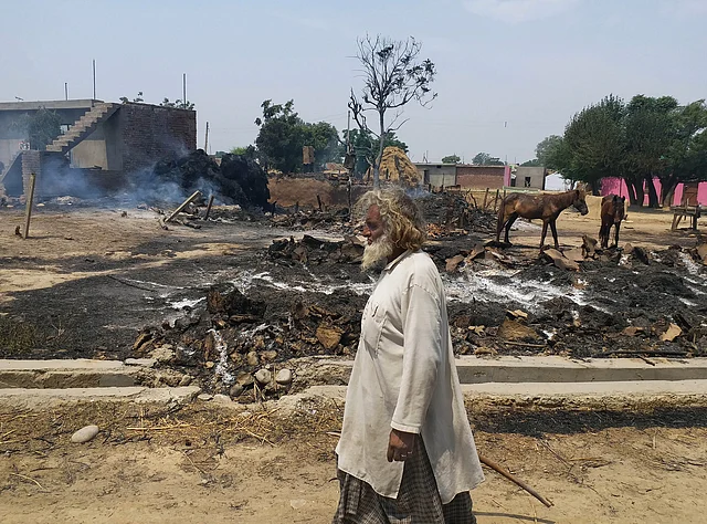 An Indian man inspects the damage after his house was gutted by firing allegedly from the Pakistan side of the border.