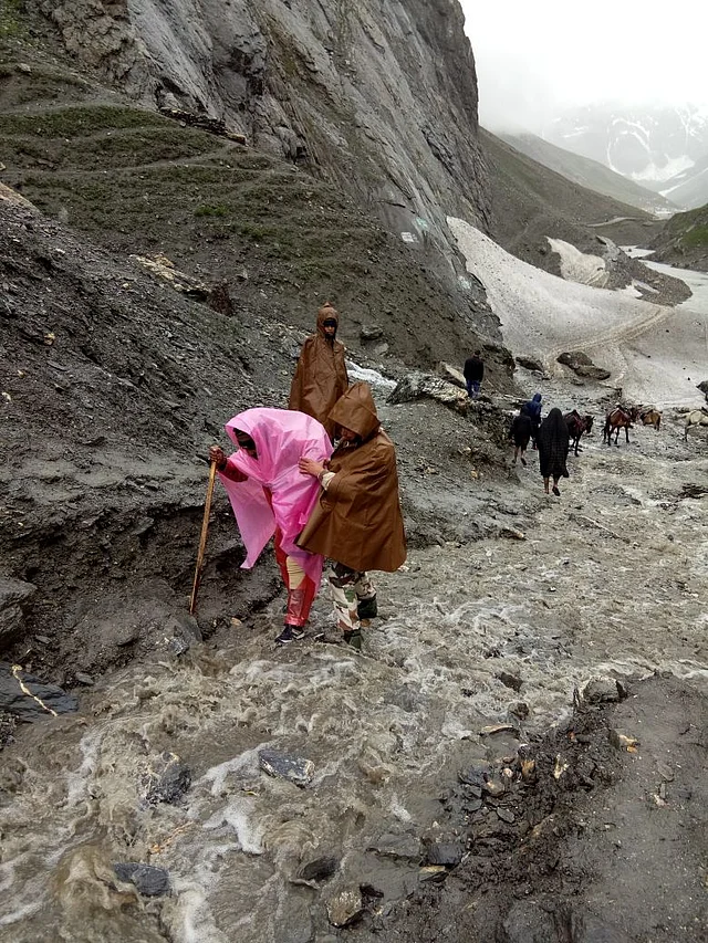 Indo-Tibetan Border Police(ITBP) personnel help pilgrims cross difficult terrain. The Amarnath Yatra was halted due to heavy rainfall in the region on 30 June, 2018.