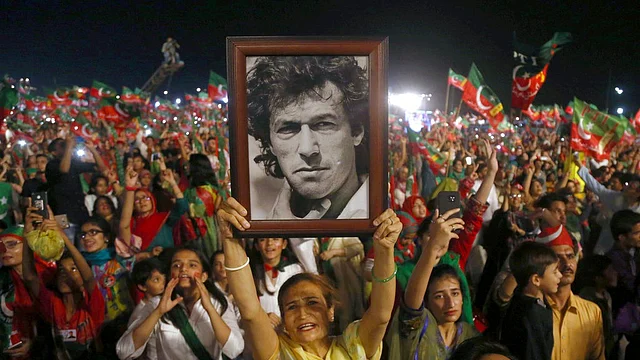 In this 22 July 2018, file photo, a woman supporter of Tehreek-e-Insaf party raises a picture of her party’s leader Imran Khan during an election campaign rally in Karachi, Pakistan.