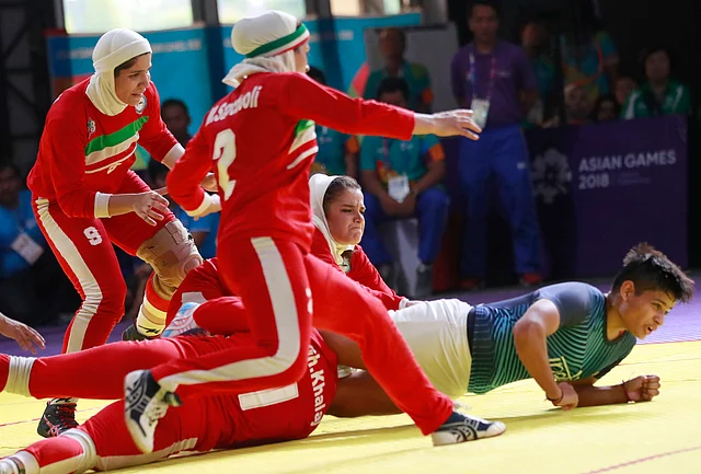 India’s Sakshi Kumari, in blue, is caught by Iran’s team during the women’s Kabaddi gold medal match at the 18th Asian Games in Jakarta.