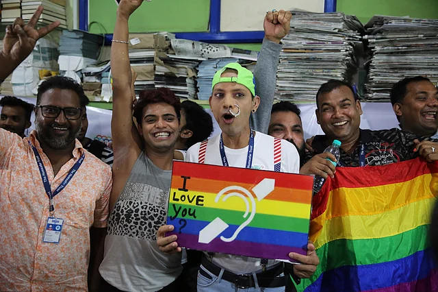 Activists posing with the posters and the LGBTQ flag in Mumbai.