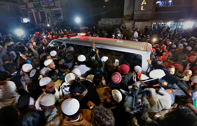 Haq’s followers crowding the van in which his body is being carried. 