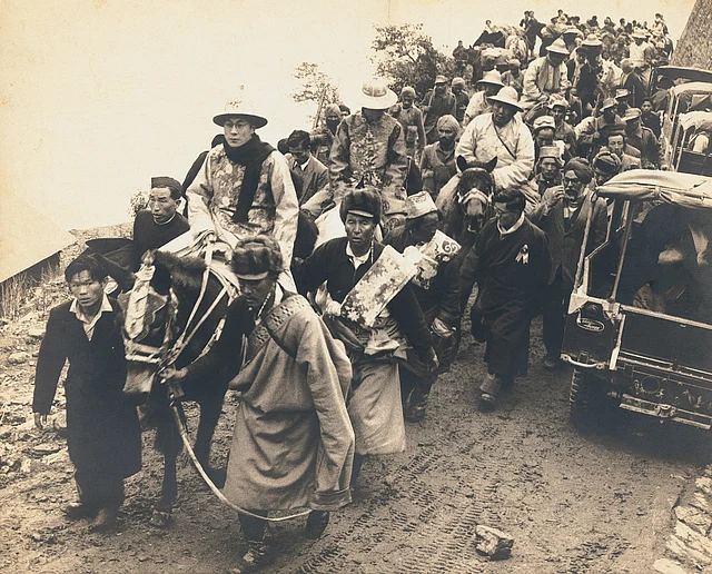 The Dalai Lama, in ceremonial dress, enters India through a high mountain pass. He is followed by the Panchen Lama. Sikkim, 1956