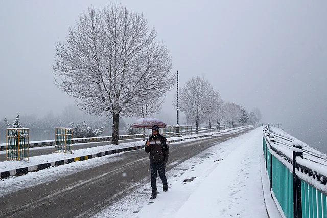 A man walks along a street as it snows on the outskirts of Srinagar in Kashmir, 19 January 2019. The fresh snowfall has resulted in disruption of air traffic and road traffic between Srinagar and Jammu, the summer and winter capitals of the Indian state.
