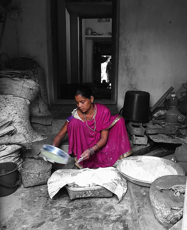 Sanju <i>didi </i>sieves finger millet flour for her SHG’s enterprise. 