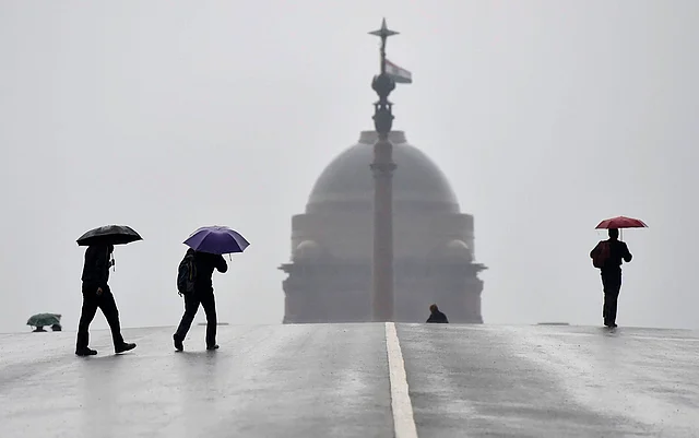 People walk on a road during rains on a cold morning at Raisina Hills, in New Delhi on 22 January 2019.