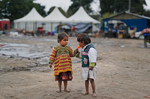Homeless children share an ice lolly in New Delhi, India, on 24 January 2019.
