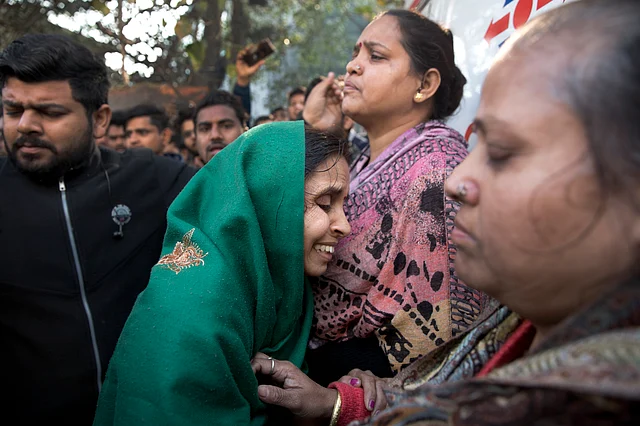 Unidentified relatives gather outside after an early morning fire at a hotel in the Karol Bagh. 