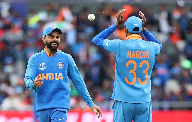 India's captain Virat Kohli, left, smiles as he throws the ball towards his teammate Hardik Pandya during the Cricket World Cup.