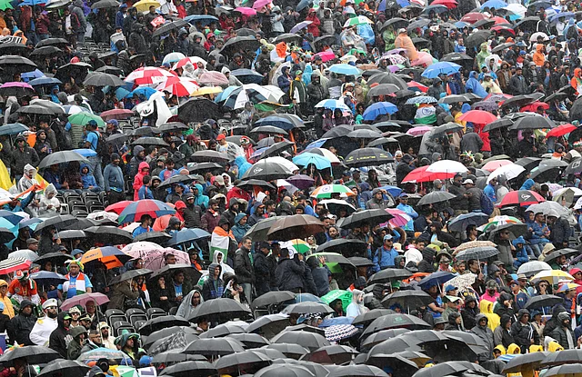 Spectators stand under their umbrellas after rain stopped play during the Cricket World Cup match between India and Pakistan at Old Trafford.