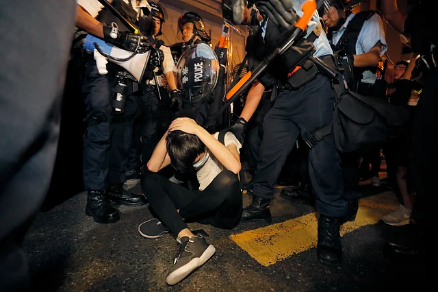 A protester attempts to cover himself as police officers in anti riot gear approach, during a rally against the proposed amendments to the extradition law, at the Legislative Council in Hong Kong during the early hours of Monday, 10 June.