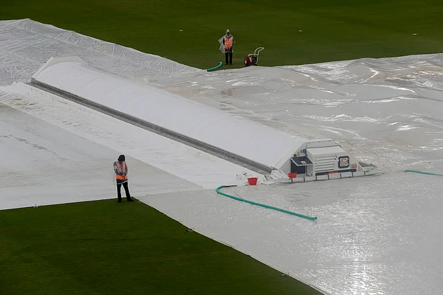 Stewards stand alongside rain covers on the pitch after play was stopped due to rain during the World Cup cricket match between South Africa and the West Indies at The Ageas Bowl in Southampton.