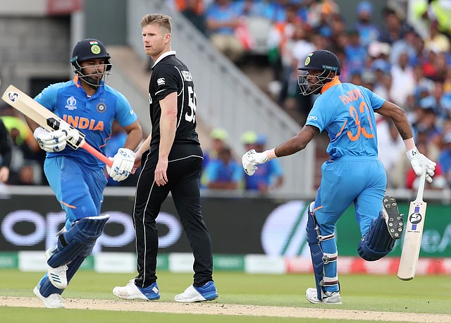 New Zealand’s James Neesham, center, watches as India’s Hardik Pandya, right, and Rishabh Pant run between the wickets to score during the Cricket World Cup semi-final.