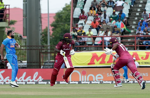 India bowler Mohammed Shami, left, watches to the outfield as West Indies opening batsmen Chris Gayle, center, and Evin Lewis, right run between the wickets during their first One-Day International cricket match in Providence, Guyana.