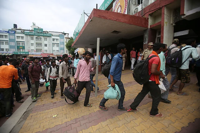 Indian migrant labourers carry their luggage and prepare to leave the region, at a railway station in Jammu.