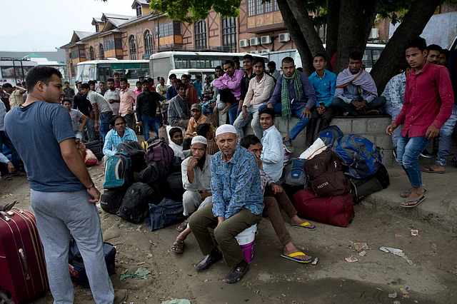 Indian migrant workers wait outside the government transport yard waiting to buy bus tickets to leave the region, during curfew in Srinagar, Indian controlled Kashmir.