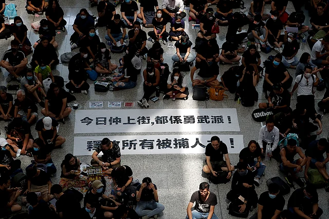 Protesters surround banners that read: “Those on the street today are all warriors!” top, and “Release all the detainees!” during a sit-in rally at the arrival hall of the Hong Kong International airport