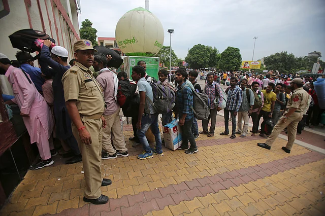 Indian migrant labourers carry their luggage and prepare to leave the region.