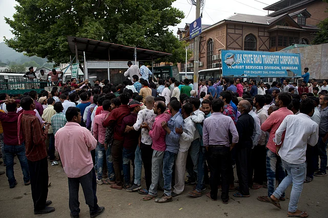 Indian migrant workers wait outside the government transport yard waiting to buy bus tickets to leave the region.