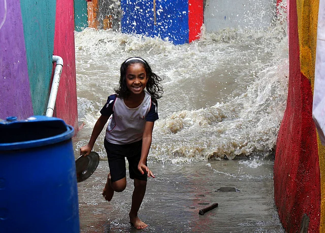 In this 3 August 2019 photo, a girl runs as waves from high tide enter a shanty area in Mumbai.