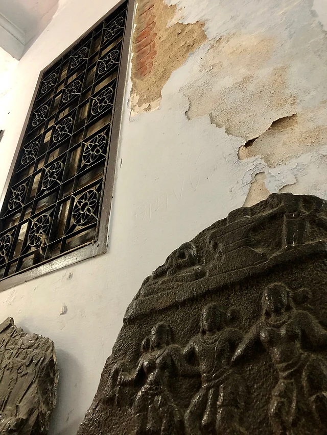 The sculpture of devotees dancing under a Shivalinga, flanked by a crumbling wall.