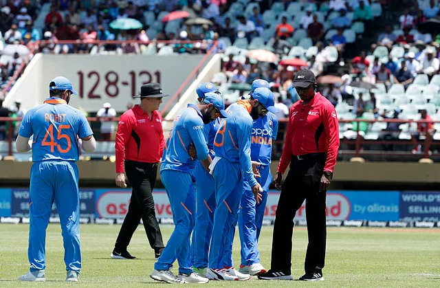 India’s cricket player and umpires inspect the pitch after rain stop during their first One-Day International cricket match in Providence, Guyana.