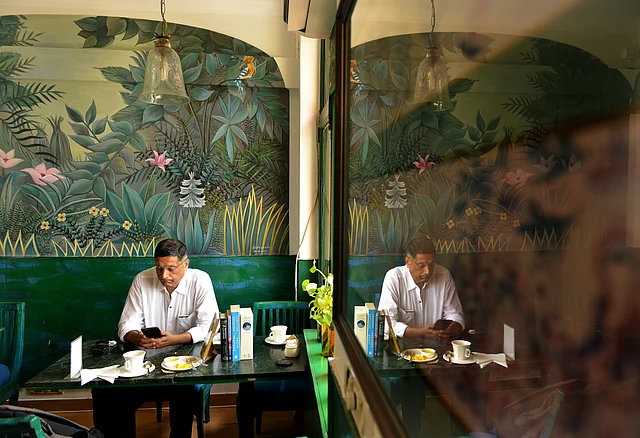 Indian economist and the former Chief Economic Adviser to the Government of India, Arvind Subramanian reading in a cafe. Khan Market, New Delhi, 2019.