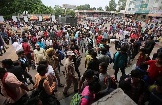 Migrant labourers carry their luggage and prepare to leave the region, at a railway station in Jammu.