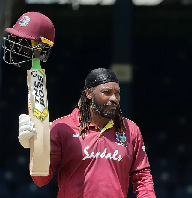West Indies opener Chris Gayle raises his bat to the crowd after reaching a half-century on the third One-Day International cricket match India.