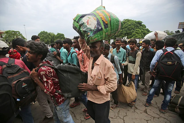 Indian migrant labourers carry their luggage and prepare to leave the region, at a railway station in Jammu.