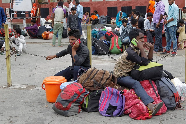 Indian migrant labourers speak on their mobile phones as they prepare to leave the region, at a railway station in Jammu.