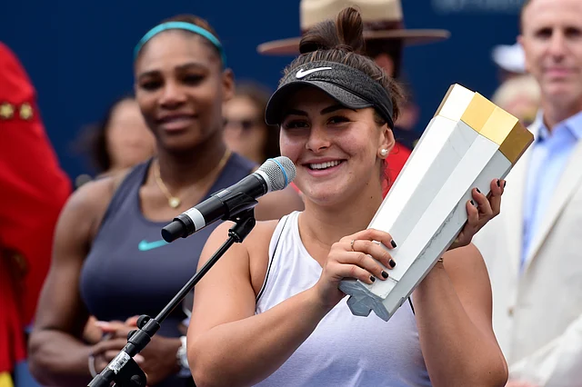 Canada’s Bianca Andreescu holds the winner’s trophy as Serena Williams of the USA looks on after Williams had to retire from the final of the Rogers Cup tennis tournament in Toronto on Sunday, Aug. 11, 2019. 