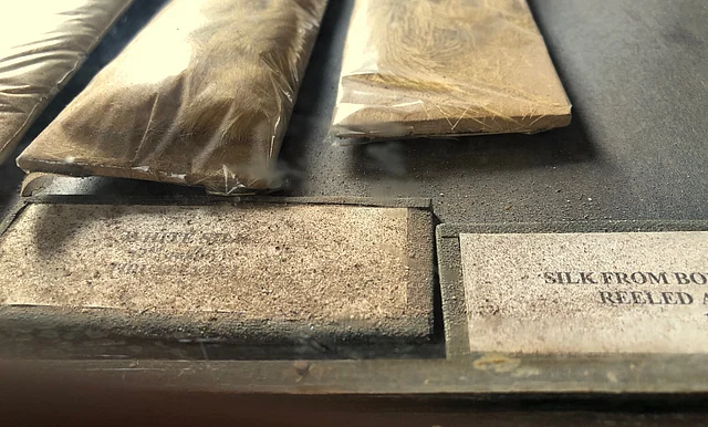 Section on fabrics, specifically types of silk. The exhibits are falling apart, and exposed to direct sunlight under a glass case.