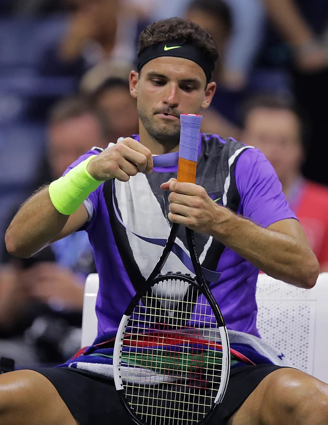 Grigor Dimitrov, of Bulgaria, tapes his racket grip before facing Roger Federer, of Switzerland, in the fifth set during the quarterfinals of the U.S. Open tennis tournament Tuesday, Sept. 3, 2019, in New York.