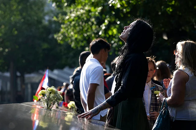 A woman stands next to the north pool prior to a ceremony marking the 18th anniversary of the 11 September attacks at the National September 11 Memorial in New York. 
