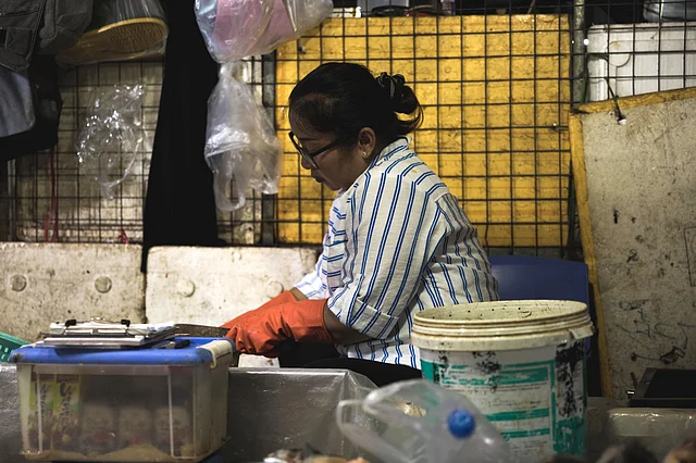 A woman skins the fish before it is sold to a customer