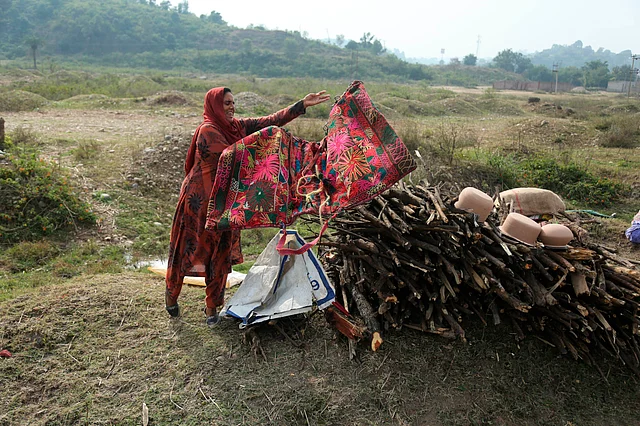 An Indian nomadic Gujjar woman dries her clothes on the outskirts of Jammu, India, on Wednesday.