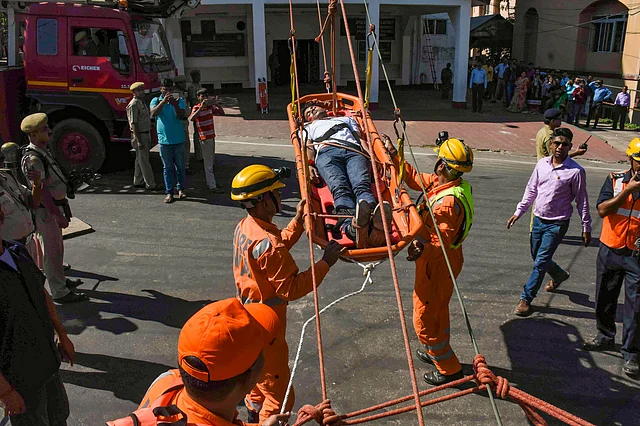 Fire service personnel carry a school boy during a mock rescue operation drill, in Agartala on Thursday.