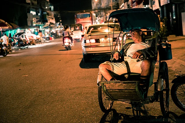 A middle-aged rickshaw-puller sleeps on his rickshaw during the wee hours of the morning. Rickshaw-pullers in Phnom Penh are usually in their 20s or past their 60s.
