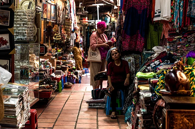 She guards her shop and looks at passersby hoping they would visit her shop. 
