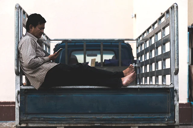 A rarely-sighted middle-aged worker rests after he’s done unloading his truck at a go-down. Usually, it's young laborers doing this kind of heavy lifting.