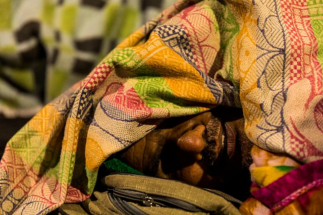 He wraps himself in his quilt to keep himself warm as he sleeps on his bag. 